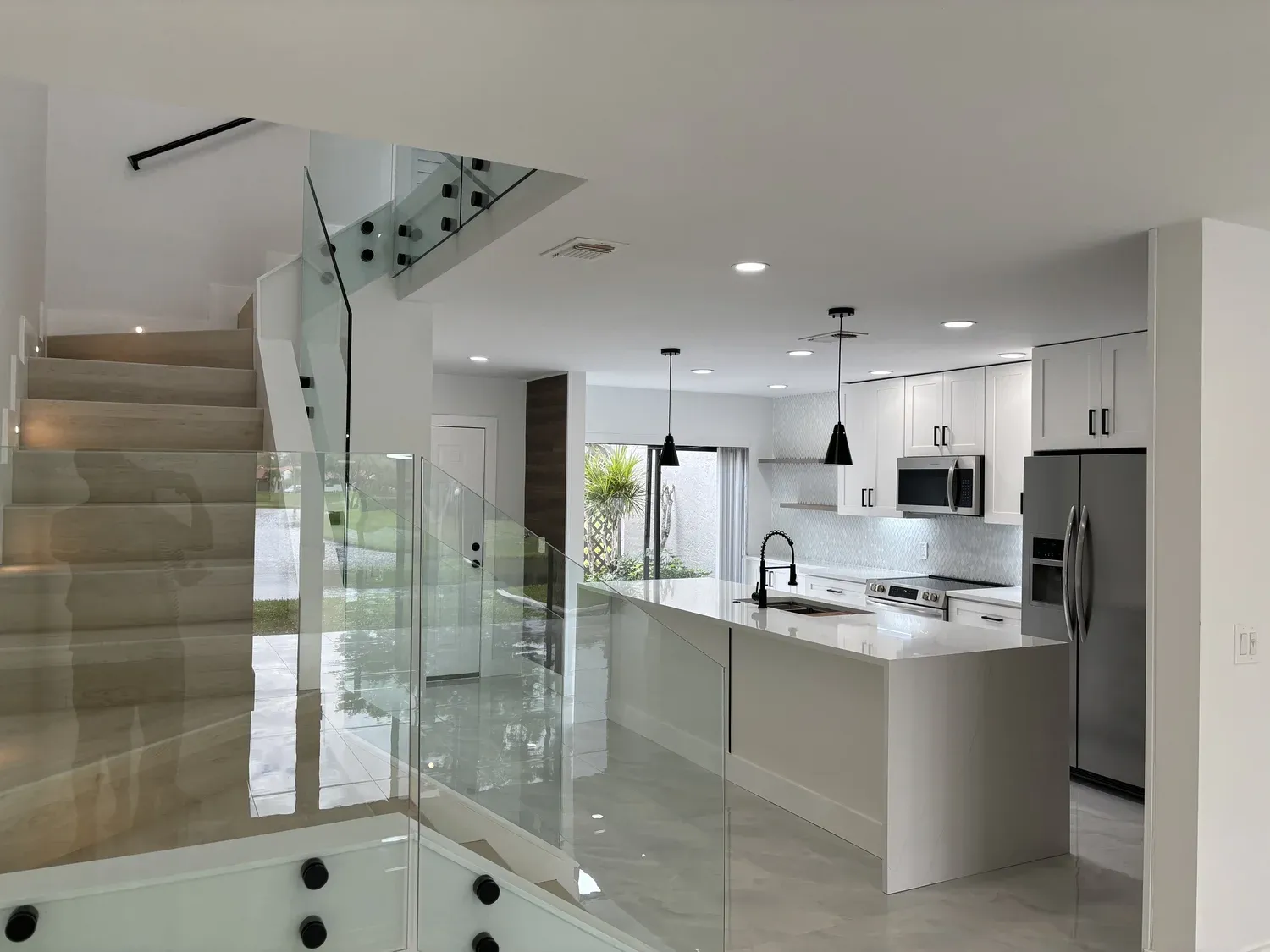 Open-concept kitchen with island and staircase with glass railing