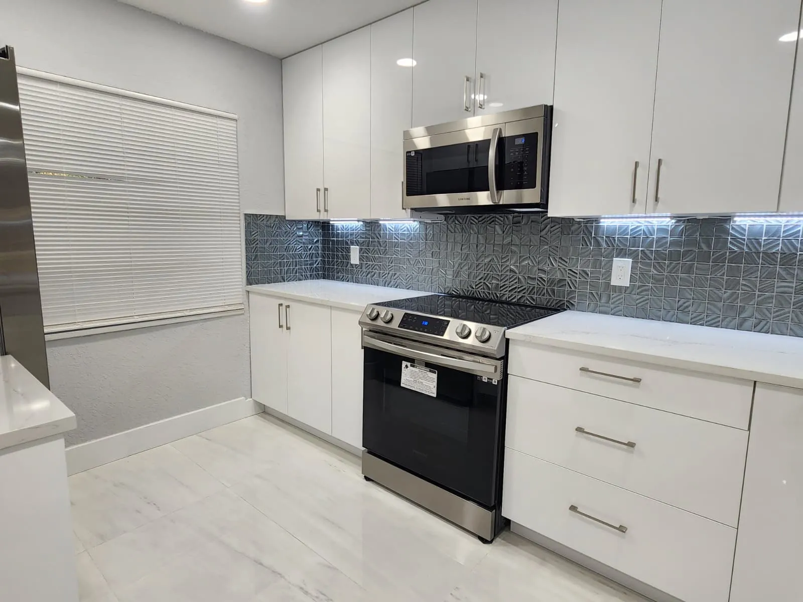 Modern white kitchen with quartz counters and tile backsplash